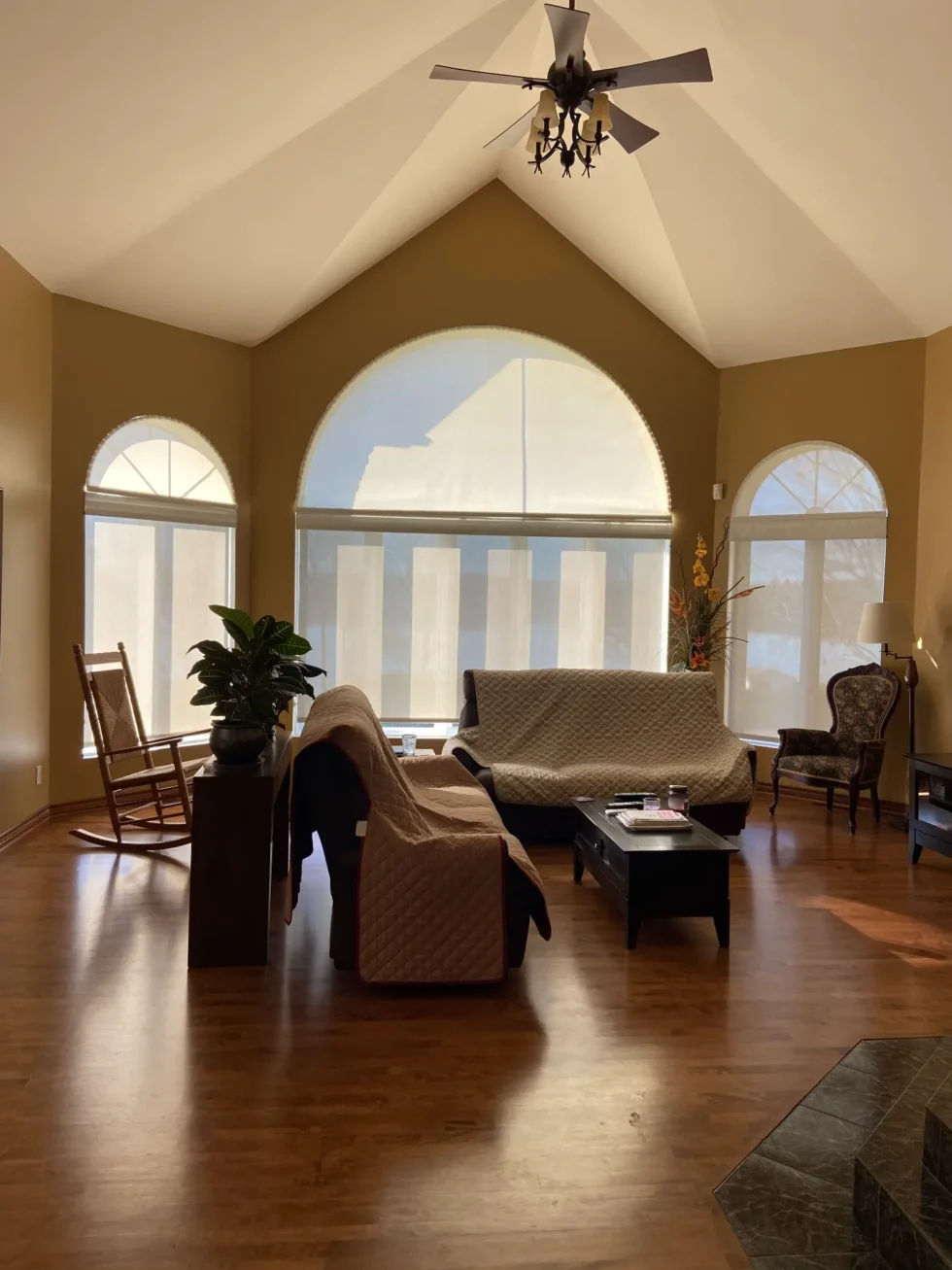 Espace salon spacieux avec planchers de bois, grandes fenêtres arquées et aménagement d’origine – image avant transformation.