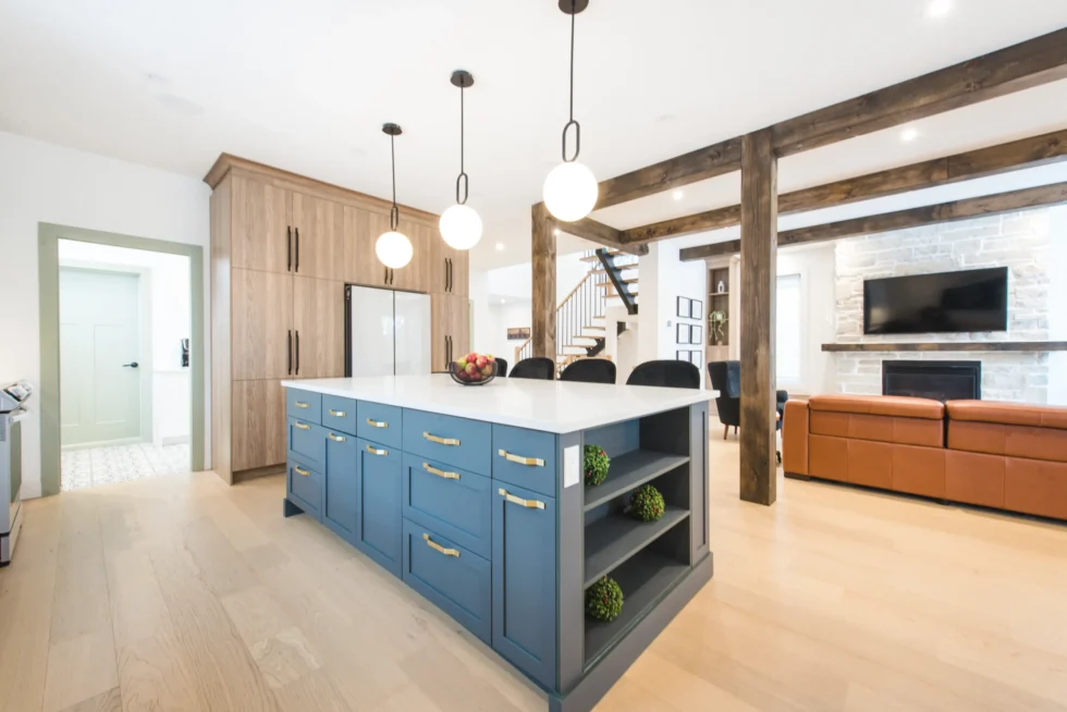 Cuisine contemporaine avec îlot bleu central, suspensions modernes et armoires blanches – design raffiné par Catherine Paradis, T.P.